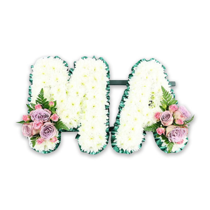 A personalised funeral flower tribute spelling out the letters MA rests in the centre of a white background, the design calm and balanced, like a carefully arranged display at a West Norwood memorial service. The robust frames of the letters are entirely hidden under an abundance of white chrysanthemums, each flower head positioned closely to its neighbours so the entire surface appears luxuriously padded. The chrysanthemums' petals are fine and slightly curved, giving the letters a soft, ruffled texture that feels gentle on the eyes and subtly luminous under the light. Around the perimeter of both the M and the A, a deep emerald edging defines the shape. This looks to be created from a tightly folded satin ribbon or carefully applied foliage, tracing every turn of the letters with a consistent, polished line. The contrast of dark green against bright white offers a sense of order and refinement, much like the neat floral arrangements often seen lining the aisles of local West Norwood chapels. Nestled at the base of the left leg of the M and the right leg of the A are two small but expressive floral sprays. These are made from soft pink roses, lilac roses, and petite pink spray roses that sit atop the chrysanthemums in graceful, rounded mounds. The roses vary in openness, some just beginning to loosen their petals, others fully unfurled to reveal intricate spirals. Among them, airy fern fronds and slim stems of greenery lend lightness and dimension, suggesting the delicate movement of foliage in a nearby garden. The composition feels harmonious and intentional, a tribute that balances formality with tenderness. It would be a meaningful piece to place beside a coffin or remembrance table in West Norwood, silently voicing love, respect, and a heartfelt farewell to Ma.