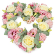 A beautifully detailed, heart-shaped condolence wreath in soft pastels stands out against a crisp white background, its design conveying quiet love and remembrance. The heart is densely packed with flowers, giving a plush, continuous surface of petals that feels both comforting and sincere. Creamy yellow and ivory roses create the main structure, their spiralled centres and velvety outer petals forming generous, rounded blooms that exude a sense of calm dignity. Between these roses, clusters of pastel pink carnations nestle closely together, their ruffled, multi-layered petals adding a gentle, textured softness, like a reassuring hand held during a service in West Norwood. Deeper magenta-pink lisianthus blossoms appear throughout, their slightly flared, trumpet-shaped blooms and silken petals providing richer accents of colour, reflecting the more intense emotions present at a farewell. Silvery-green eucalyptus leaves weave in and out of the design, their smooth, rounded foliage tracing the outline of the heart and offering cool contrast to the warm floral tones, reminiscent of the greenery around West Norwood Cemetery and nearby streets. Tiny yellow-green buds peek from among the petals, symbols of freshness and the resilient thread of life that runs through even the saddest moments. The heart shape is clearly defined and symmetrical, evoking devotion, gratitude, and lasting connection. With its blend of cream, pink, and green, this wreath would make a thoughtful funeral tribute, a memorial arrangement, or a gesture of sympathy delivered to local chapels, churches, or family homes in SE27, expressing what many find hard to say aloud during times of loss.