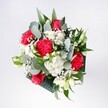 A hand-tied bouquet brimming with red and pink roses, velvety carnations, white daisies, and airy gypsophila is captured in soft natural light, as if placed on a windowsill in a quiet West Norwood terrace. The roses sit confidently at the heart of the arrangement, their petals rich and layered, surrounded by ruffled carnations in shades of scarlet and rosy pink that add movement and warmth. Snowy daisy-style chrysanthemums and tiny clusters of baby's breath form a delicate halo, their crisp white petals catching the light like a scattering of morning frost over Brockwell Park. Eucalyptus stems curl through the bouquet, their silvery-green leaves lending a cool, contemporary edge and a hint of herbal fragrance that contrasts beautifully with the sweetness of the blooms. Deeper tropical foliage frames the flowers, glossy and structured, giving the design a modern, slightly sculptural feel. The overall composition feels relaxed yet carefully balanced, as though an experienced local florist has just finished shaping it on a workbench near West Norwood station. Every stem has its place, but nothing appears rigid or overworked, creating an impression of joyful ease. The colours are vivid without being loud, an inviting mix that suggests happy occasions: a birthday gathering in a Norwood Road café, a surprise congratulations delivered to a home near the cemetery, or a welcoming bouquet set on a hallway table. The image conveys not just flowers but a sense of calm optimism, as if this bouquet has the quiet power to brighten an overcast South London afternoon and bring a touch of celebration into everyday life.